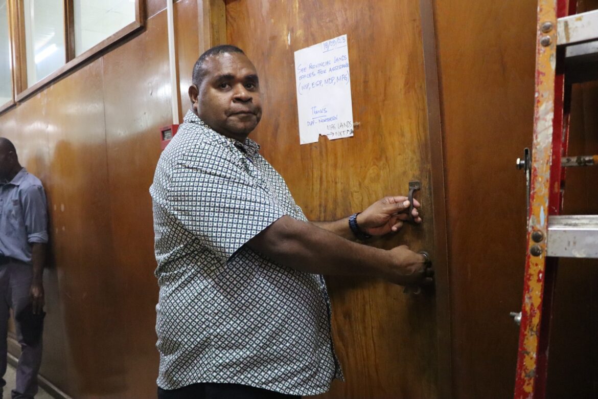 Man wearing a grey shirt holding a key and locking the DLPP door