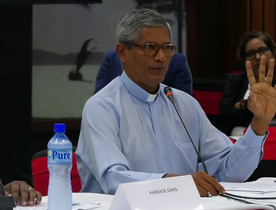 Father Ambrose Pereira: Teach Media Literacy Priest Fr Ambrose Pereira wearing a button up white shirt holding one hand up and speaking about media literacy.