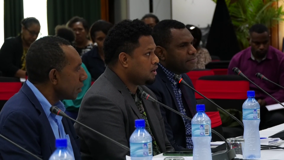 Side shot of three men in suits sitting at a table