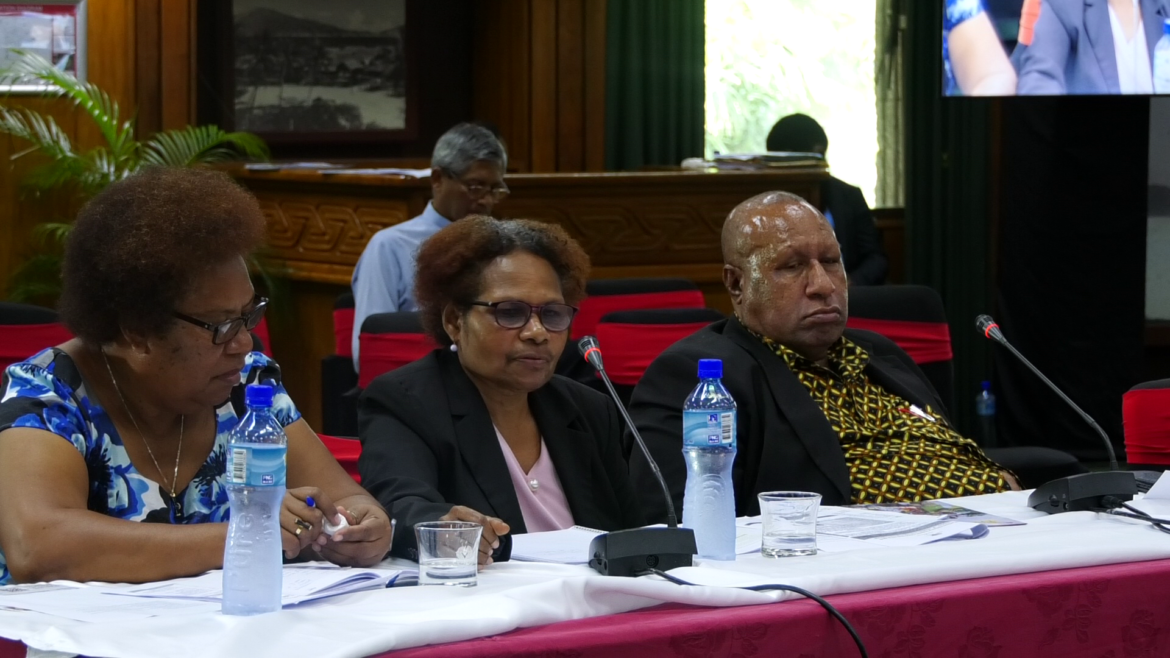Two women and a man sitting a table.