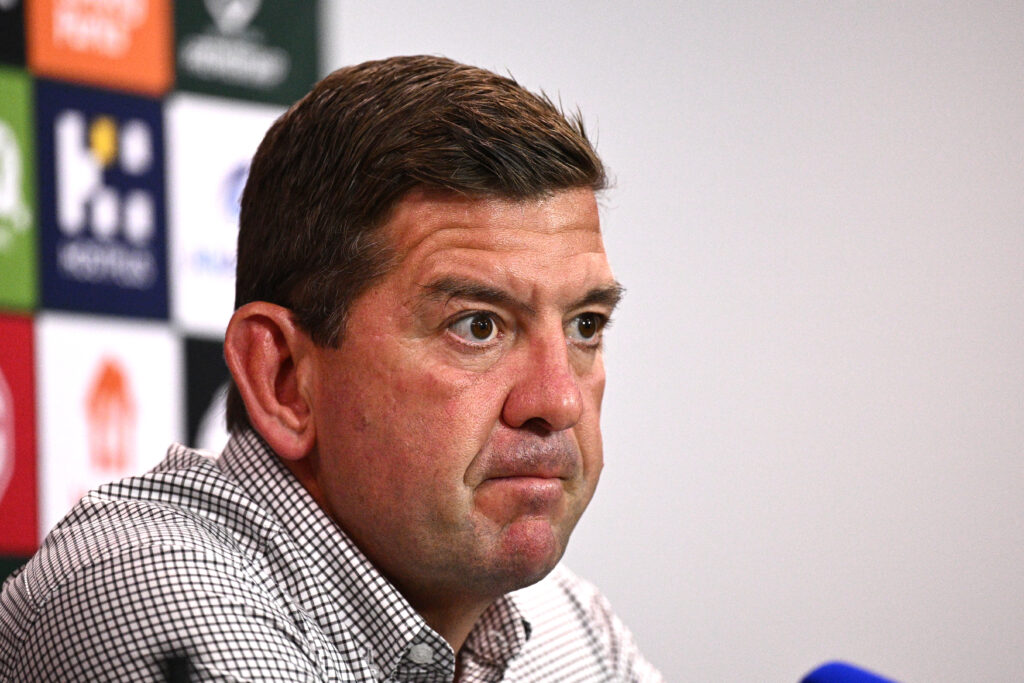 Off the side headshot of Rabbitohs head coach, Jason Demetriou. Wide-eyed Caucasian man with brown hair and stubby nose. 