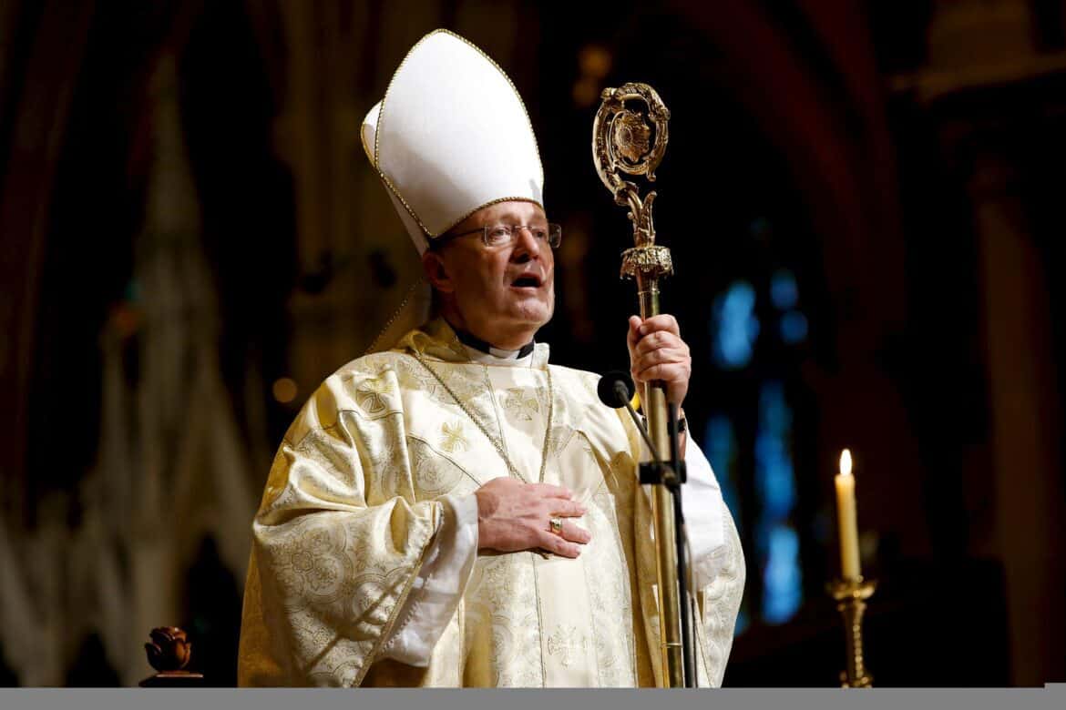 Pope Francis in white holding a staff and one one hand on his chest