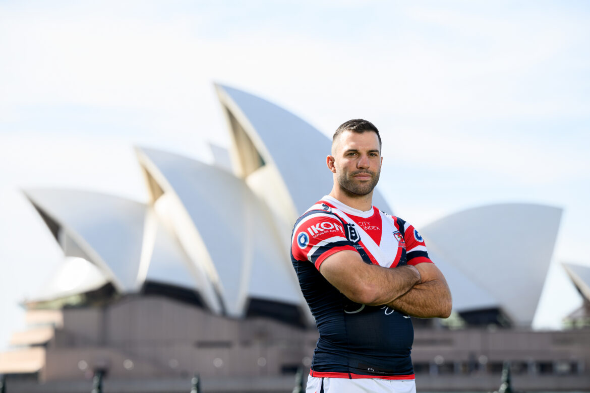 James Tedesco wearing a Rooster Jersey standing with his arms crossed in front of the Sydney Opera House.