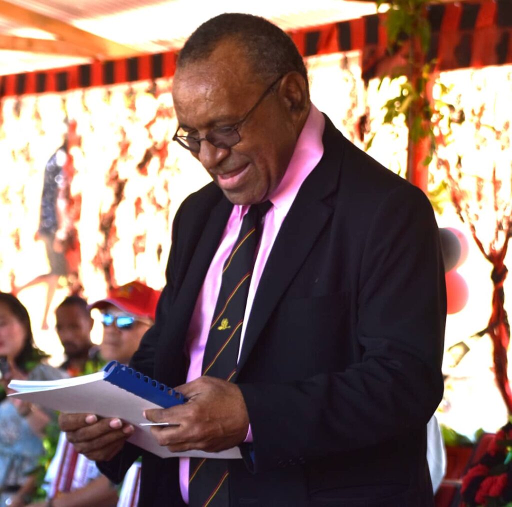 Waigani Christian College founder, Benjamin Mul, holding a book on stage.