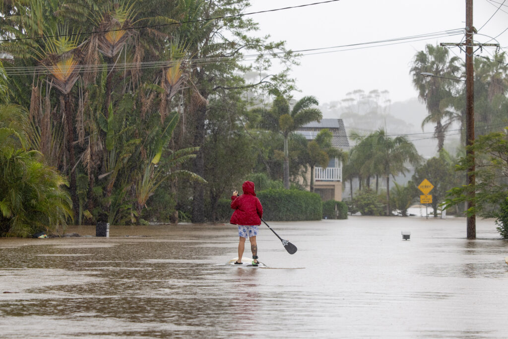 Thousands of homes damaged after deadly, record floods A person uses a paddleboard on a flooded street in Port Macquarie, New South Wales, Friday, May 23, 2025. (AAP Image/Lindsay Moller)