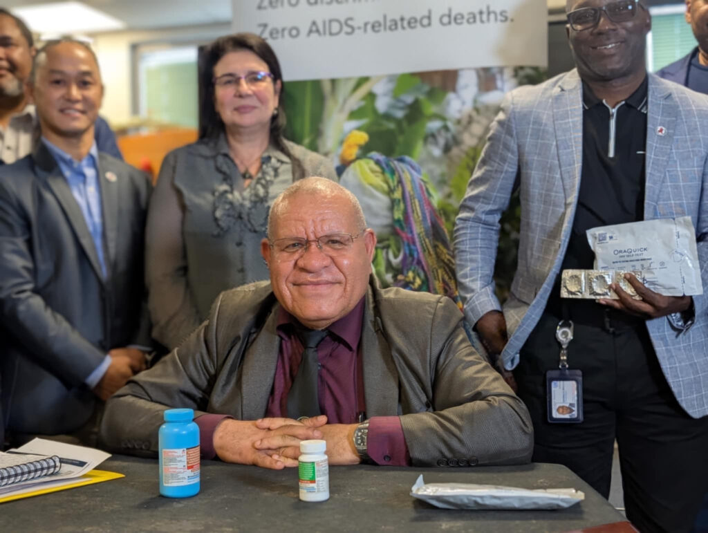 Bald brown man wearing a suit, Ken Wai comments on HIV crisis in PNG