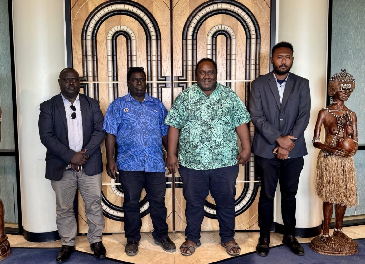 Four men standing between two carvings