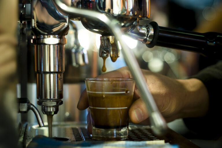 Coffee dripping from a Nespresso machine into a small cup
