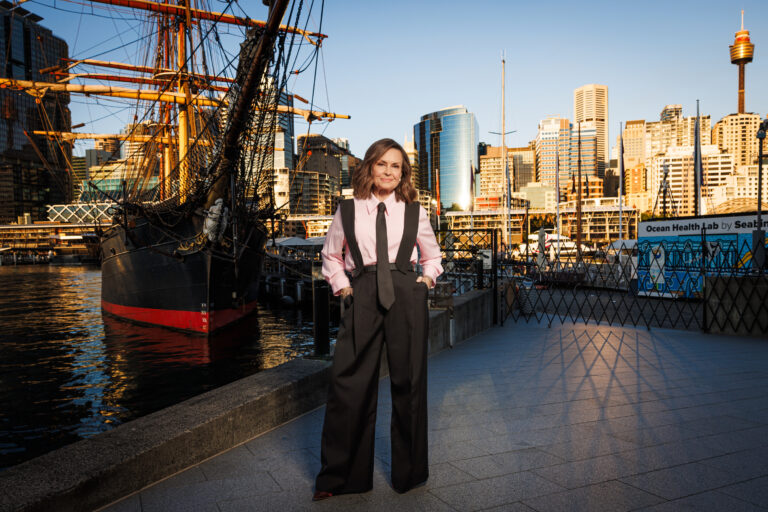 Titanic rewritten in heroic tale of Aussie survivor A women wearing a white top and long black pants standing on what appears to be a harbor with a ship in the background