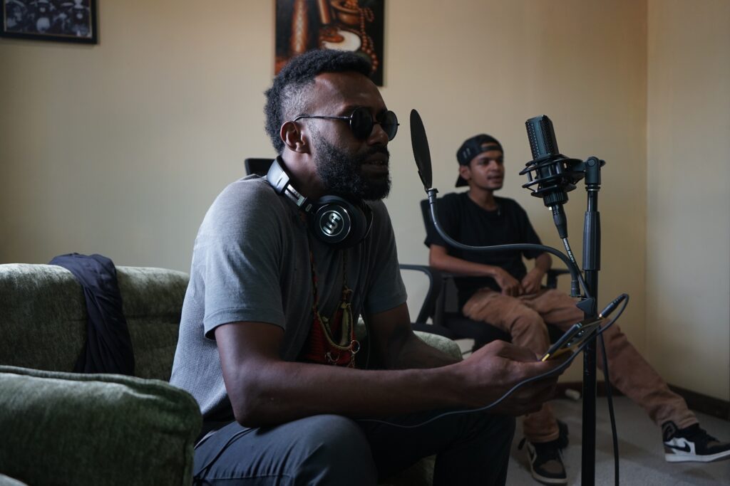 Dark skinned man recording a song on a studio mic