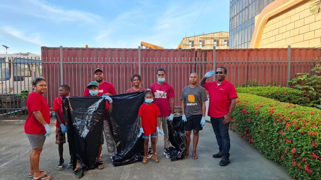 Kina bank staff and families wearing red shirts with blue gloves holding black garbage bags ahead of clean-up exercise along Wewak beach.