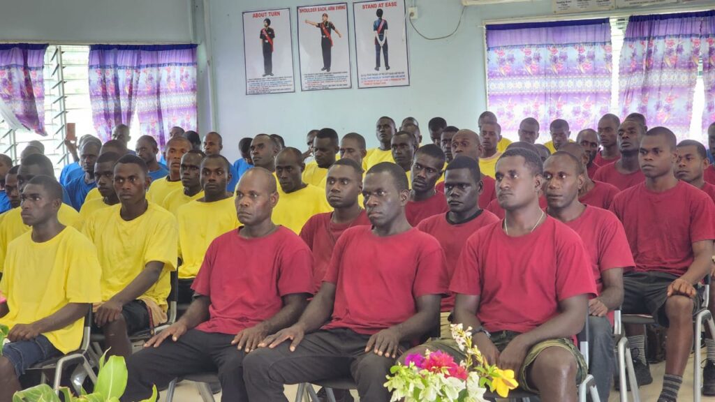 Lloyds Academy Students sitting on chairs in rows wearing red, yellow and blue.